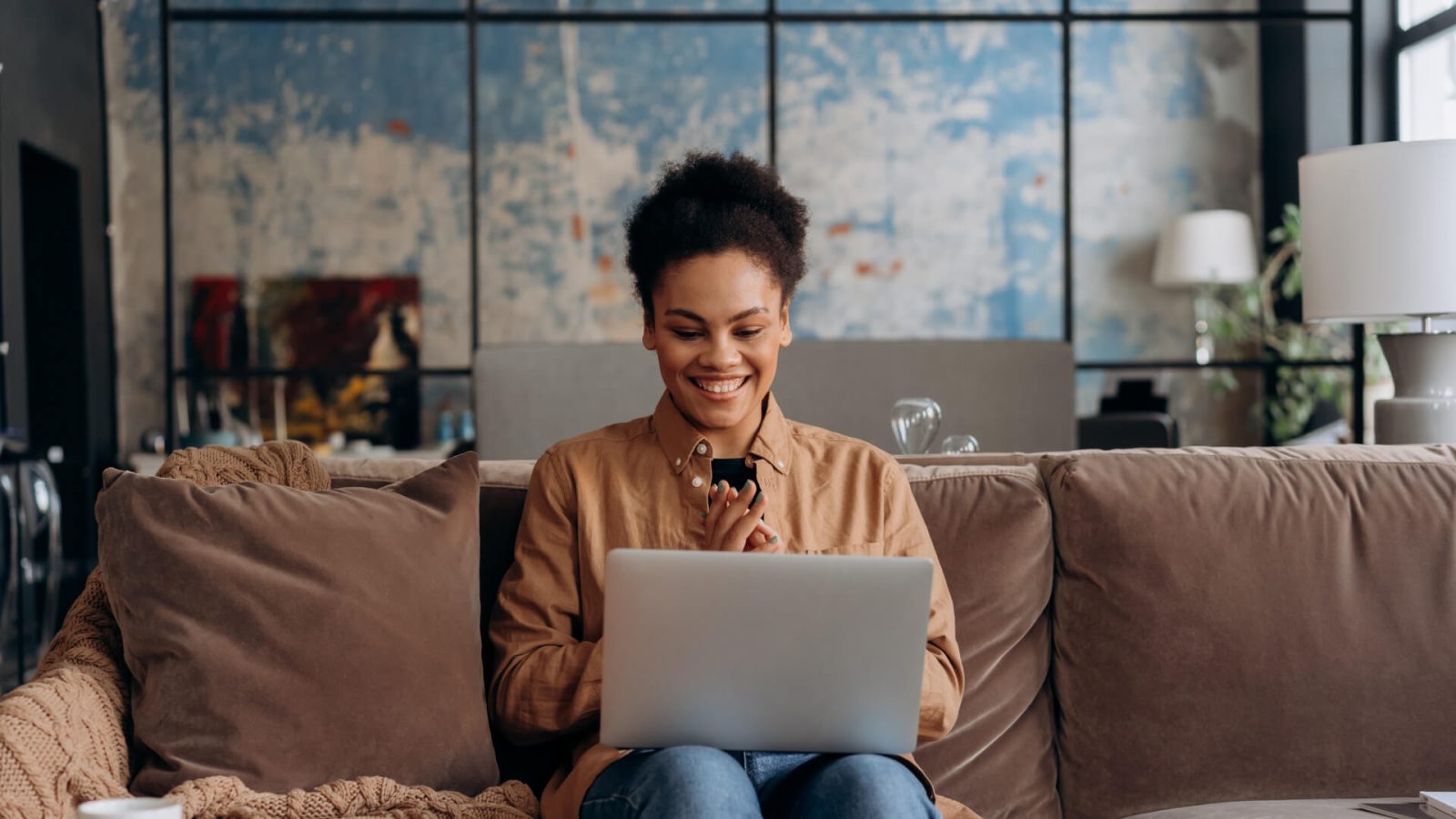 a woman sitting on a couch with a laptop at The Allure